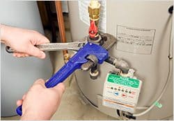 Man fixing a boiler with a blue wrench